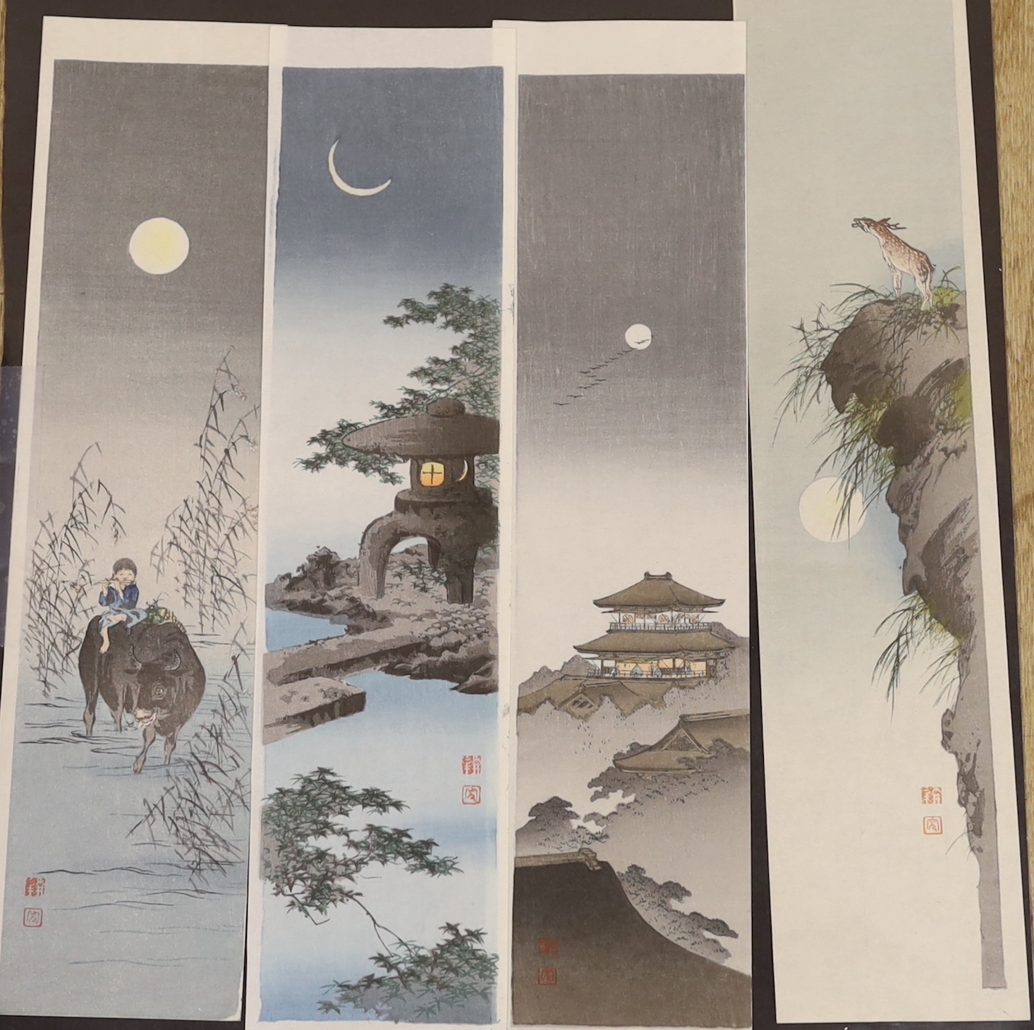 Shoda Koho (1871-1946), four unmounted woodblock prints, tanzaku format, boy and ox in moonlight, stone lantern and crescent moon, figures on a pavilion and deer on the rocky outcrop in moonlight